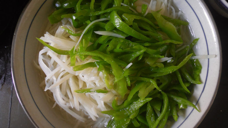 凉拌酸辣土豆丝,烫好的青椒和土豆丝要沥干水，然后放在一个大点的碗里备用。