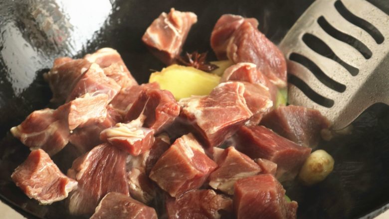 红烧牛肉面,下入牛肉块翻炒。