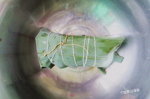 烤肉味粽子,左手把粽叶覆盖到右手的粽子上。再往下一折余下的粽叶,就包住了,左手别松手。捆绑好即可。