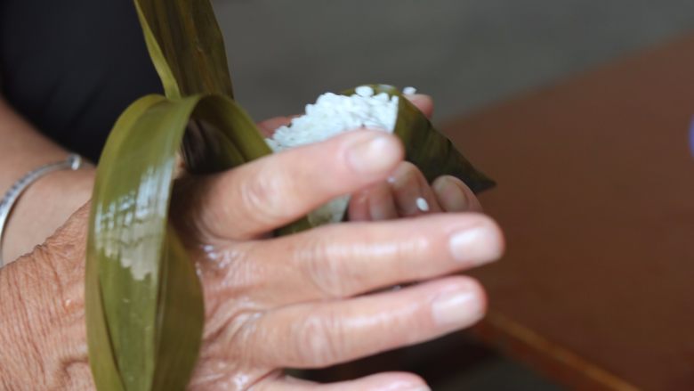 红枣粽,11.左手拿着粽子用你的右手向前推粽叶,盖上口