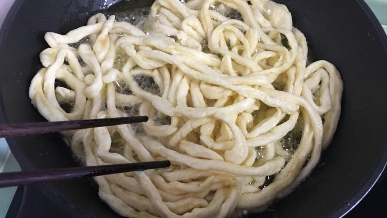 原味沙琪玛,油热后放入适量面条，然后用筷子将面条打散，油炸时不时的用筷子翻一下面条。