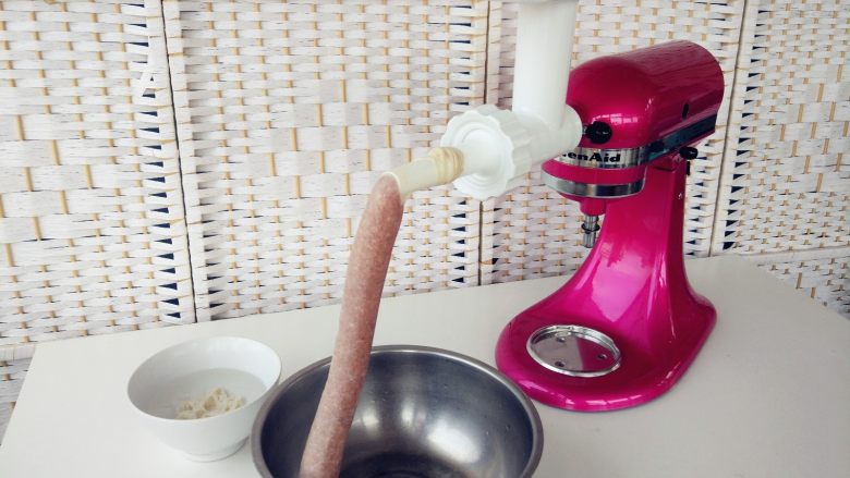 烧麦灌香肠土豆丝饼套餐,将拌好的香肠馅装入Kitchenaid绞肉器中,用手抵住出口,待肉馅出现在肠衣底端,将肠衣打结,以低速开始灌香肠,用手稍往后推肠衣,以保证肉