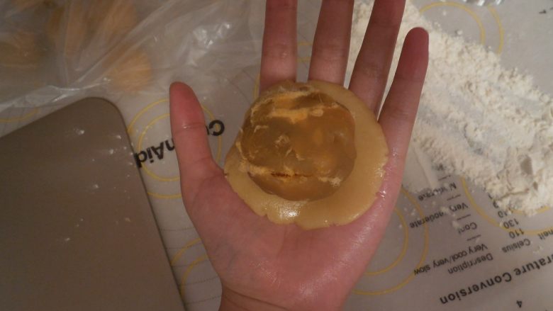 莲蓉肉松月饼,取一个面团按扁,将莲蓉肉松 放在面皮上