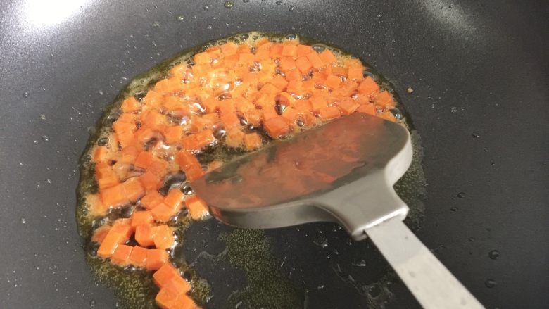 粗粮凤梨炒饭,开小火,锅内倒入少许油,加入胡萝卜丁翻炒。胡萝卜是比较硬的食材需要多炒一会儿,使β胡萝卜素溶于油,更利于营养吸收。
