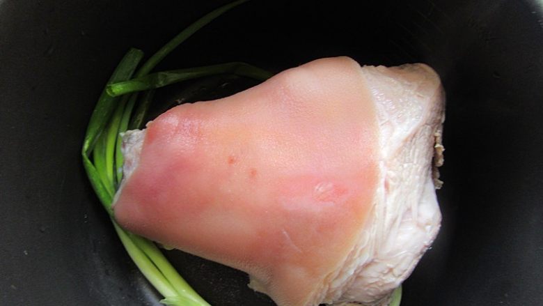 卤蹄髈,再次电压力锅或电饭煲刷干净,铺上葱和姜片,放入蹄艕