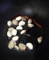扁尖焖酱鸭,坐锅点火注入油,放蒜子、姜片、干辣椒爆香。