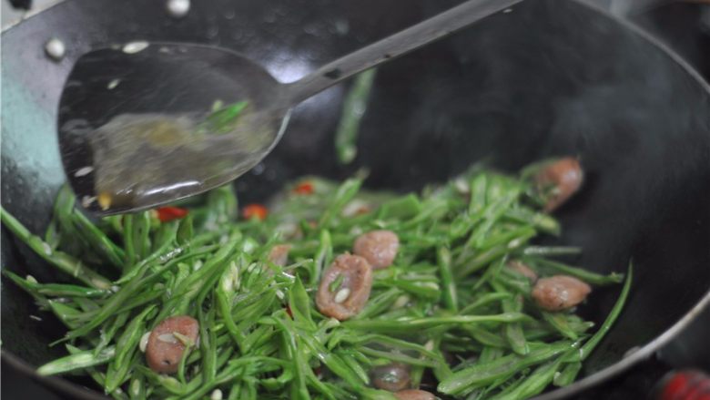 四季豆炒肉肠,倒入四季豆，沿着锅边淋入少许水