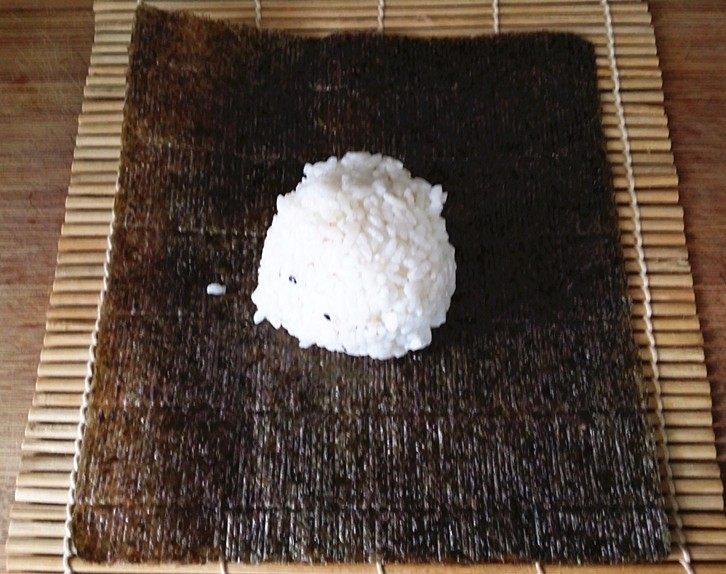 什锦火腿寿司,准备好寿司竹帘,平铺一片紫菜再放上拌好的饭团