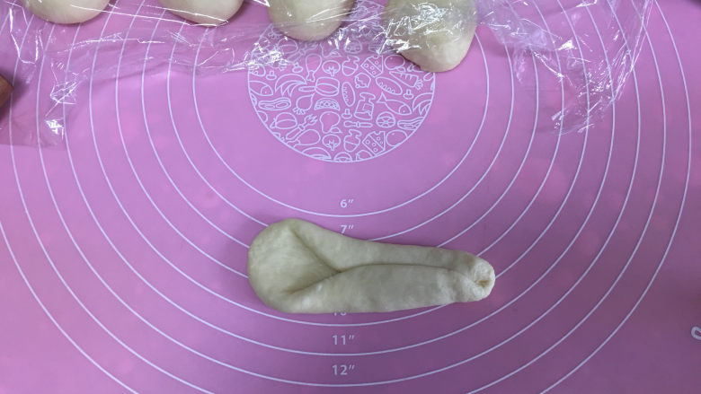 肠仔面包卷,翻面横放,将两边对折,折成一头大一头小的形状。