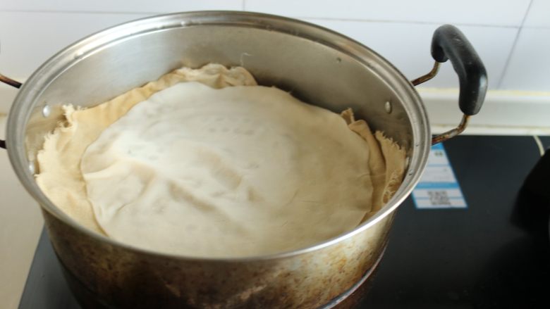 土豆丝卷饼,蒸锅加水,烧开后,篦子上垫一个纱布,把擀好的饼放在篦子上。