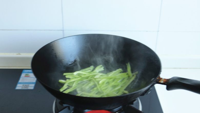 土豆丝卷饼,炒锅放油烧热后,下入青椒丝翻炒10秒钟。