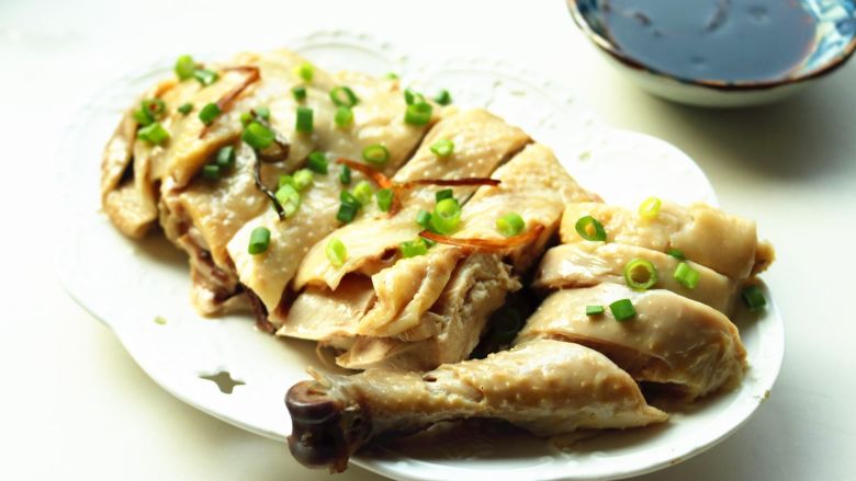 葱油白斩鸡,鸡身上撒上小葱碎,蘸着料汁食用。