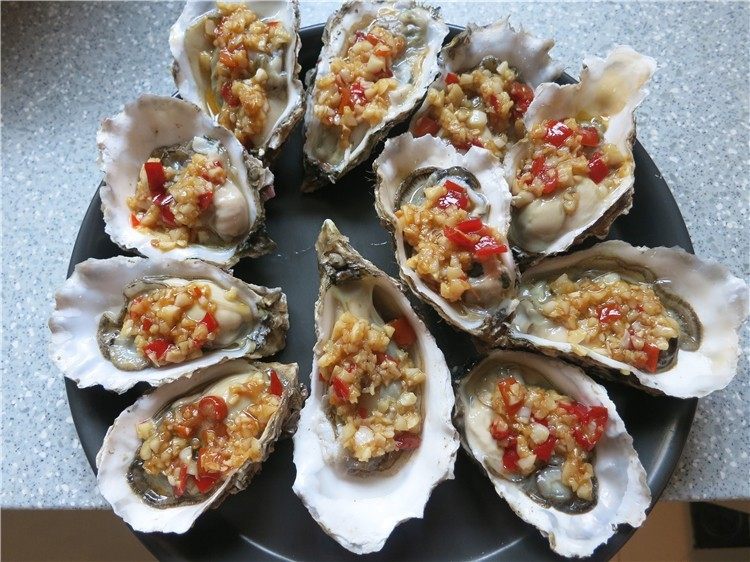 蒜蓉生蚝烤烤更美味,将炒好的蒜蓉用勺舀到生蚝上,放入披萨盘中