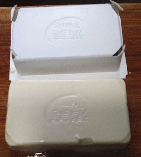 火腿豆腐羹,反扣案板上,将四角切小口,就可顺利向上提起包装盒了