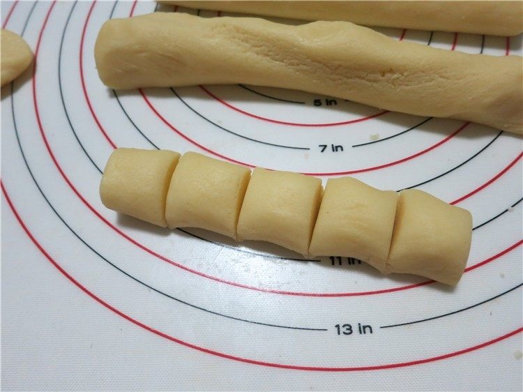 提拉米苏小饼干,7. 将面团置于硅胶案板上,整理一下切成3块搓成条,分成15克一个的小剂子