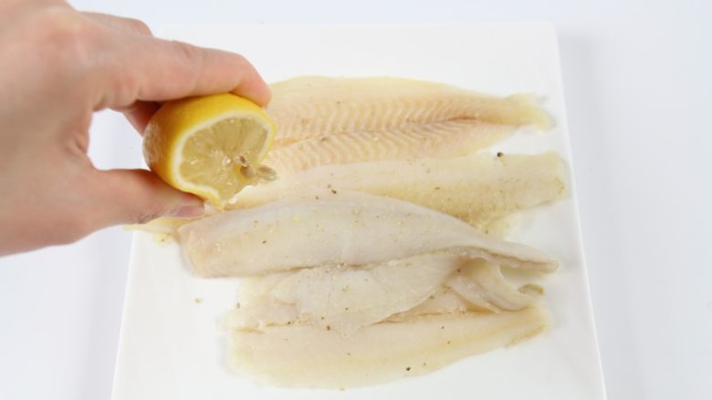香煎鲽鱼片,挤入适量的<a style='color:red;display:inline-block;' href='/shicai/ 919'>柠檬汁</a>,抹均匀,腌制5分钟左右。