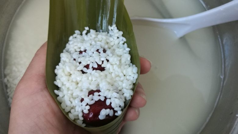 大红枣粽子,再盖上一层糯米。不能太多,煮的时候后会溢出来,也不能太少,太少的话粽子煮出来不抱团,会散影响口感