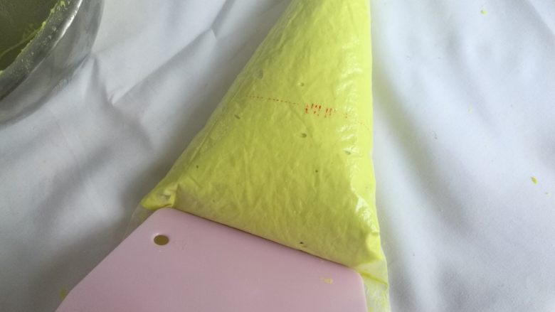 春色马卡龙,裱花袋装入中号圆形裱花嘴,装入裱花袋,用刮板推至裱花嘴处。