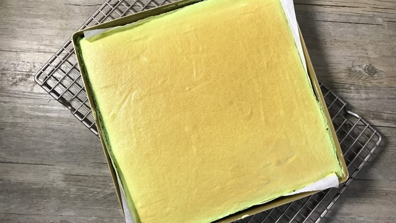 草莓斑斓蛋糕卷,出炉后震一下模并拉住油纸将蛋糕体取出待凉(稍凉后上面可覆盖一张油纸以免蛋糕表面被风干)。