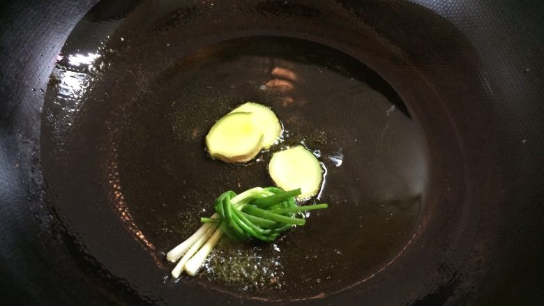 可乐鸭翅膀,锅里倒入花生油,油温7成热时,下姜片葱段煸炒。