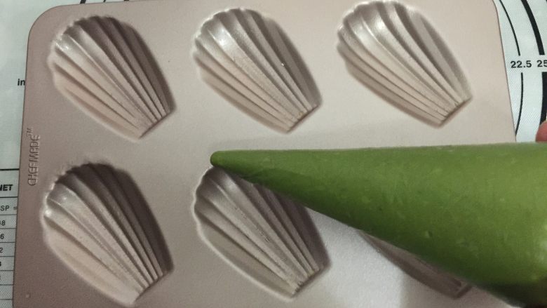 抹茶玛德琳蛋糕,把面糊放冰箱冷藏1个小时,此时面糊会变硬。将面糊在室温下回温片刻,待重新具有流动性装入裱花袋里