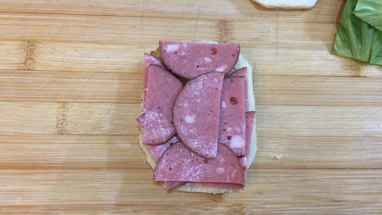 童趣早餐——乌龟全麦三明治,取一片面包片,表面铺上火腿片。
