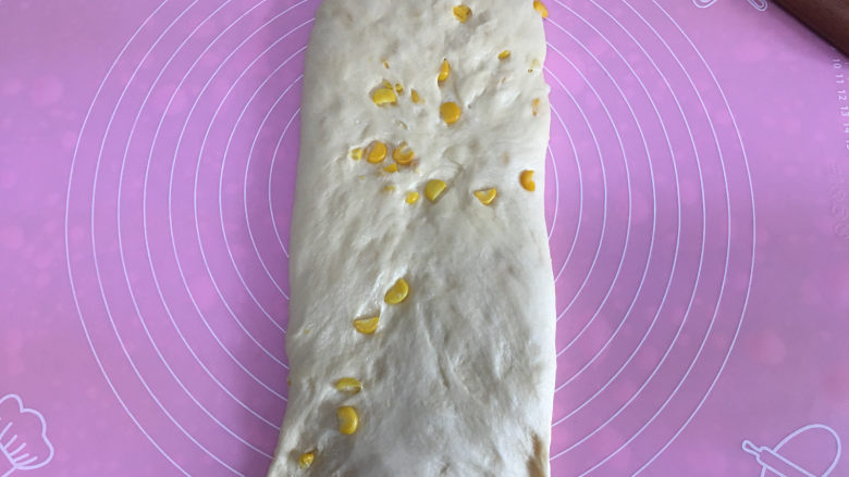 面包机版玉米吐司,发酵完毕后取出面团进行排气,然后揉圆,白擀成椭圆形,然后翻面,底部按薄。