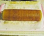 咖啡冻蛋糕卷,将油纸从起始端提起,将蛋糕卷卷起,卷到末端时用手拢紧,蛋糕卷左右两端的油纸紧紧掐紧;放入冰箱冷藏30分钟,取出切片即可