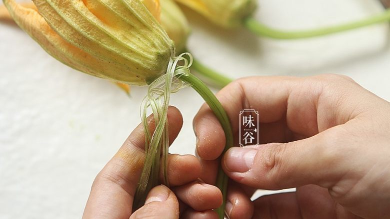 南瓜花炒鸡蛋,撕去梗部的表皮,摘去花托部位的叶子；