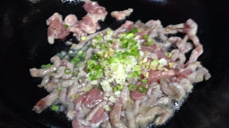 鱼香肉丝,10秒左右加入香葱粒、一半的姜、蒜碎,烹入料酒炒匀