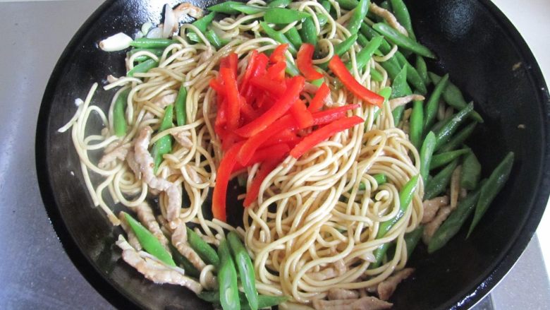 四季豆肉丝炒面,加入红椒丝进去翻炒;