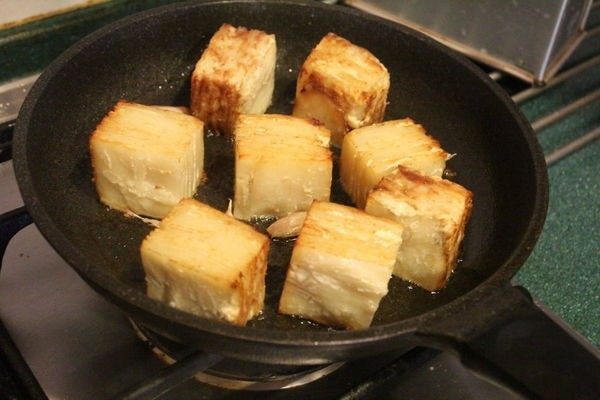 马铃薯千层方块 Potato Pavé,在室温退温30分钟。平底锅加热后,放入足够的橄榄油和几瓣连皮拍开的大蒜,小心将马铃薯块切面放入煎至有些棕焦色后,小心翻到另一切面,也是煎稍焦