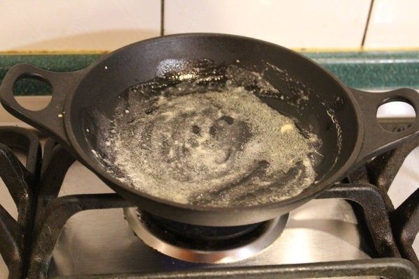Dutch baby松饼,自烤箱取出铸铁锅,小心您的手和家里的桌子,将一大匙奶油放入,摇动铁锅让奶油布满整个锅面。