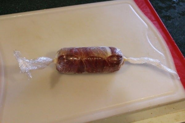 鮟鱇鱼生火腿佐芒果酱汁,用生火腿片将鱼肉卷起。再用保鲜膜将火腿鱼肉卷起,两边紧紧打结。将卷好的鱼肉卷放冰箱冷藏30分钟以上,让它定型。
