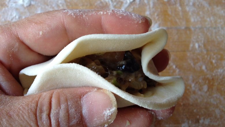 柳叶三鲜蒸饺,
用中指把面皮按向馅料方向,用手捏挤,然后用大姆指和食指托起两旁的面皮,只其形成W形。