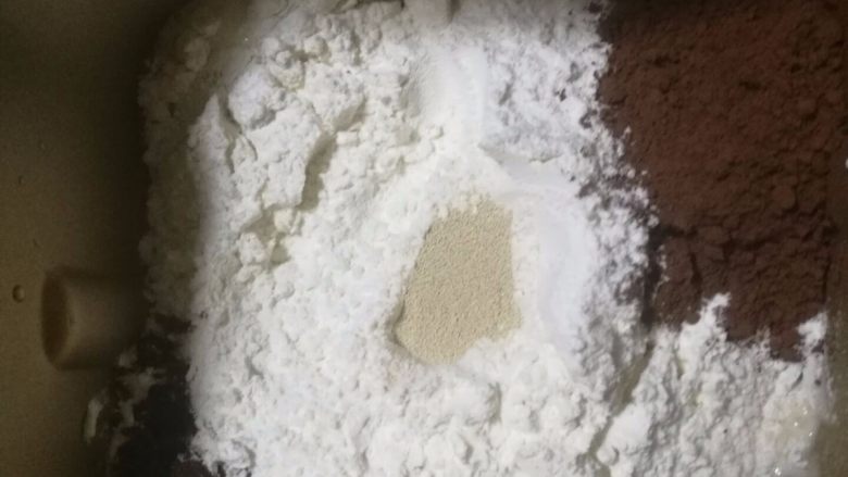 可可麻薯软欧包,制作可可面团,将面团中除黄油以外的材料放进面包机桶中,按揉面程序开始揉面,揉成光滑面团时加入软化的黄油继续揉面