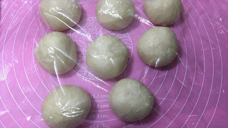 豆沙馅辫子面包(汤种法),发酵完成取出面团,进行排气,然后将面团平均分成8份,盖保鲜膜进行醒面15分钟。