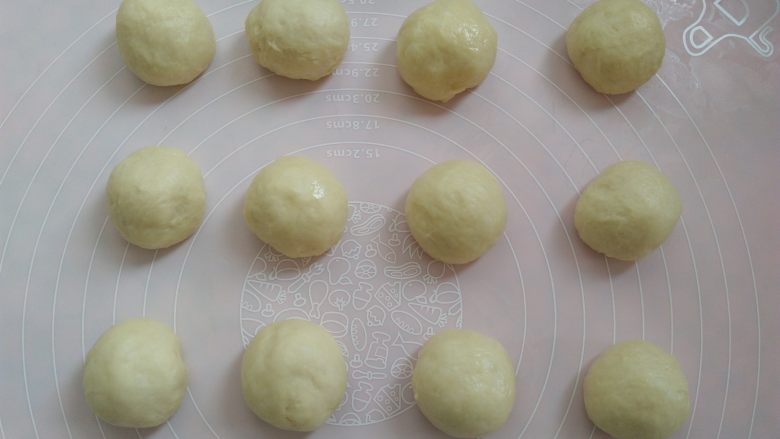 肉松花环面包,先取大的一份面团做8寸模具的花环,平均分成12个小面团,排气滚圆,盖上保鲜膜静置10分钟。再分小的面团做6寸模具的花环,一样的步骤