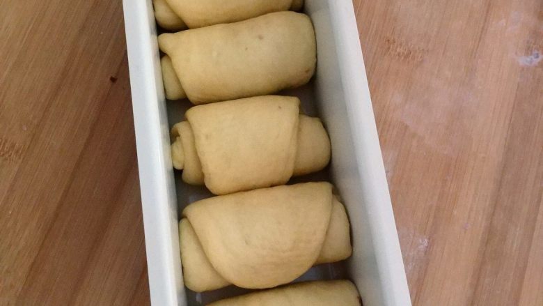 红豆吐司包,把整形发好的面团放在模具里。