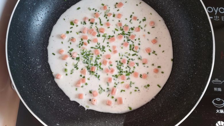 野葱鸡蛋饼儿, 在面糊上撒上适量的野葱碎和火腿肠丁,开小火煎饼