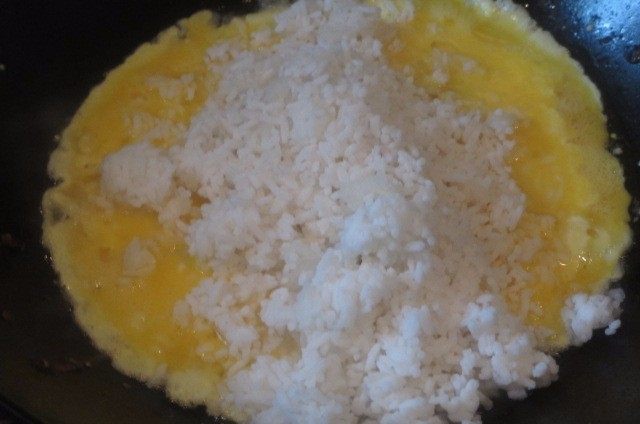 香葱炒饭,把米饭倒进去,将米粒拢至锅心,将蛋液均匀浇在饭粒上,迅速翻炒,让蛋液迅速裹住饭粒