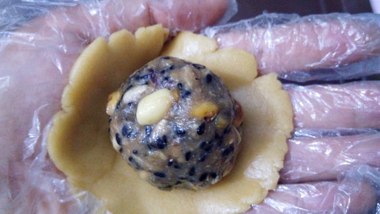 记忆中的红糖五仁月饼,戴上一次性手套,取其中一个面团用2个掌心的摩擦力按扁,放上五仁馅