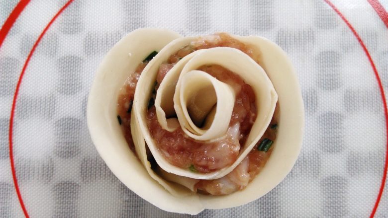 0技巧高颜值——玫瑰花饺子,卷好的玫瑰花饺子边上沾一点水,让饺子皮黏合,一朵含苞欲放的漂亮玫瑰花饺子就做好了