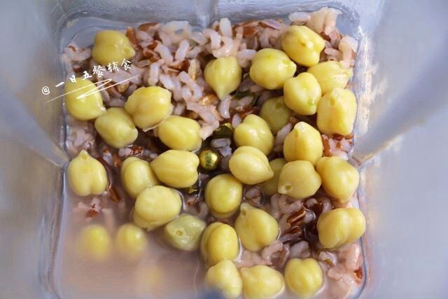 鹰嘴豆杂粮米糊,米粥煮好后,倒入搅拌杯中,再倒入煮好的鹰嘴豆。在这里需要根据米糊的稀稠度来加水做调节。