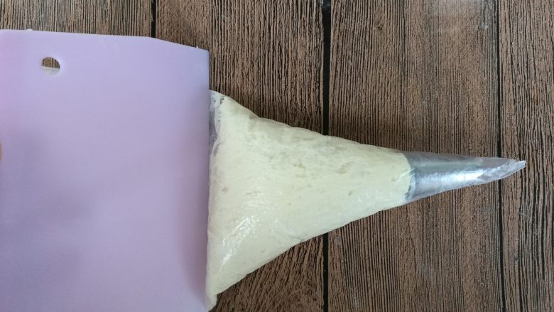 淡奶油曲奇,装入裱花袋中,用刮板擀压至花嘴处。