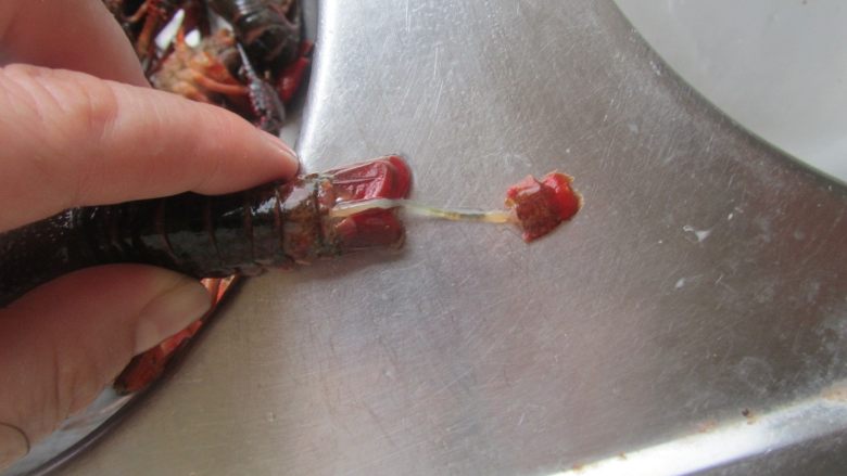 油焖小龙虾,再从虾的正面尾部的中间一片,将其虾肠从抽出来;