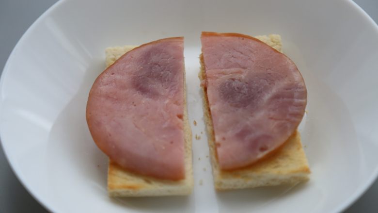 bruch之王 班尼迪克蛋,<a style='color:red;display:inline-block;' href='/shicai/ 438'>火腿</a>对半切开,放在烤好的面包片上。