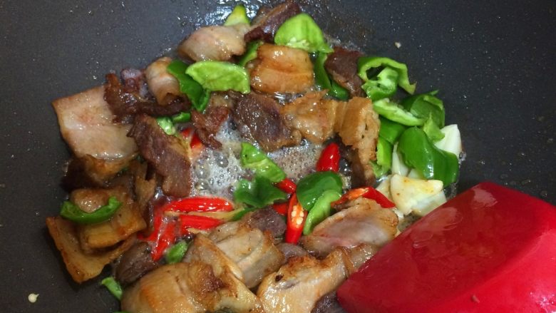 回锅肉,倒入姜丝,大蒜,青红椒继续翻炒20秒