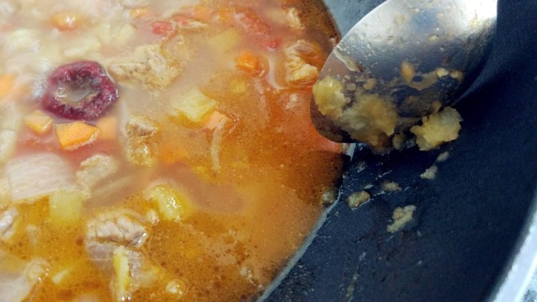 西红柿土豆炖牛肉,用勺底将部分土豆丁碾成泥,混在汤中