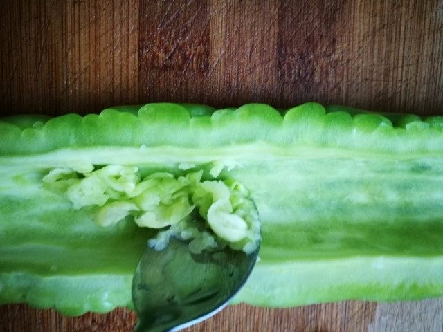 「Cathy边吃边营养」零苦味清炒苦瓜片,苦瓜切两瓣,去籽,去白膜。如果想要口感不是特别苦,就用小勺子刮掉苦瓜内层的白膜